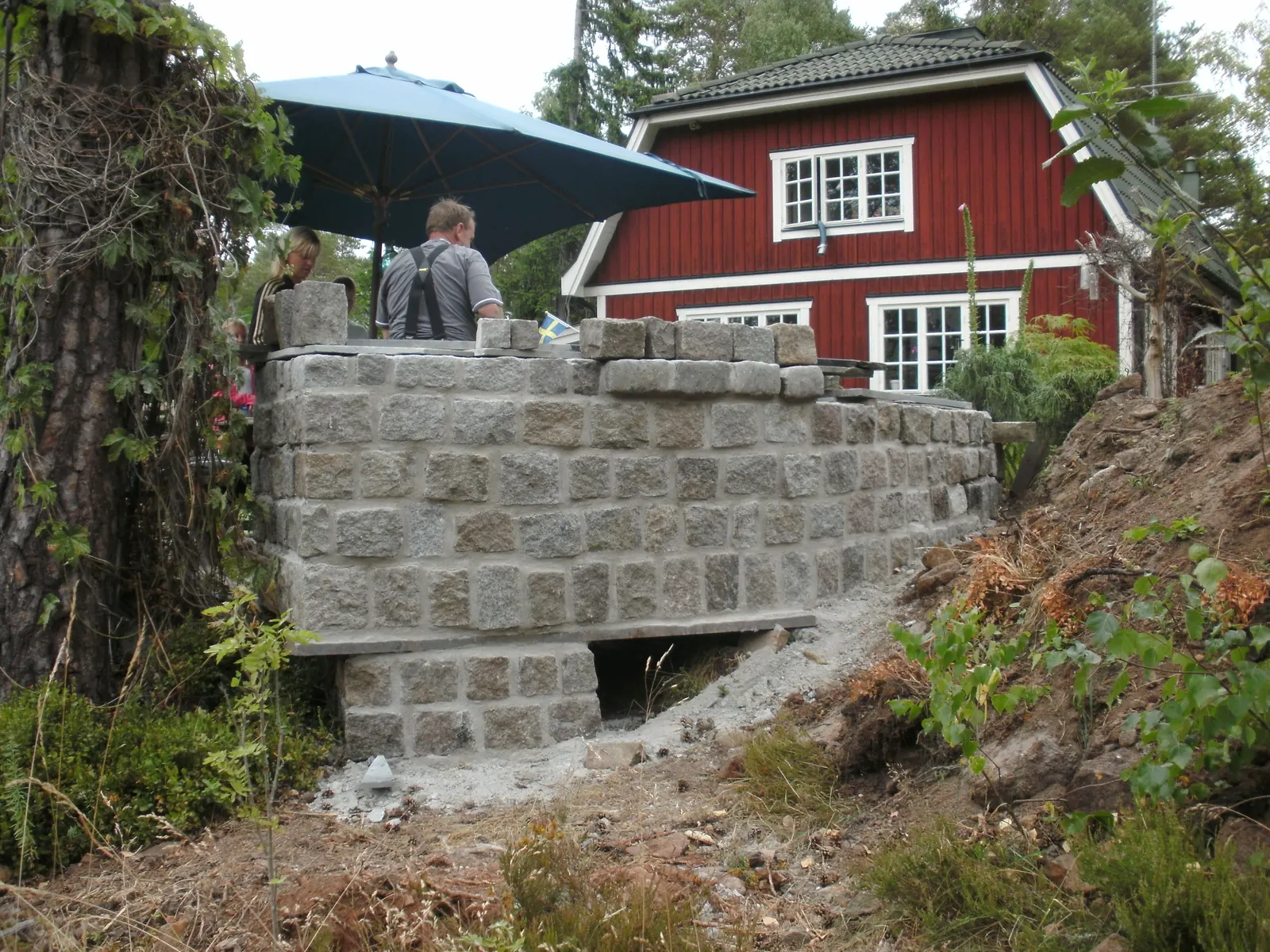 Utekök under uppbyggnad med naturstensbas i terräng